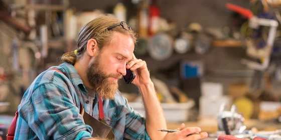  Handwerker telefoniert mit Handwerker-Handy
