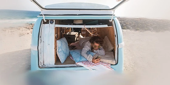  Reise-App: Mann im Auto am Strand
